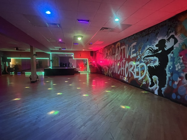 Active + Anchored studio floor with neon accent lighting and the signature graffiti mural wall