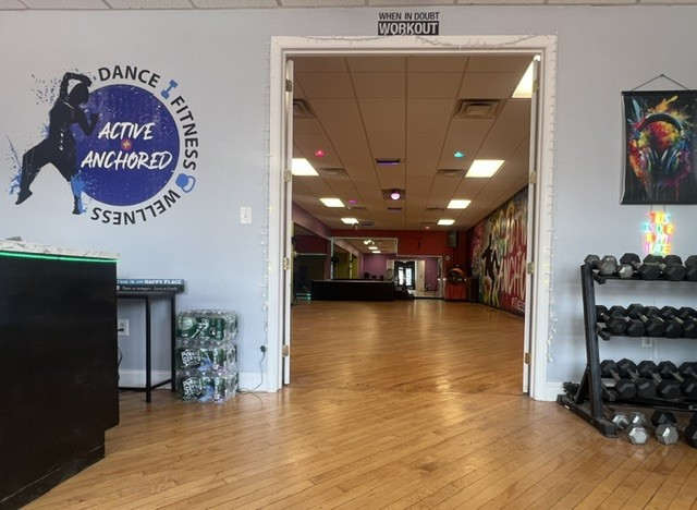 View into the Active + Anchored studio through the entrance, with the branded logo wall and weight rack
