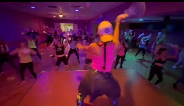 High-energy dance fitness class in the Active + Anchored studio with colorful stage lighting